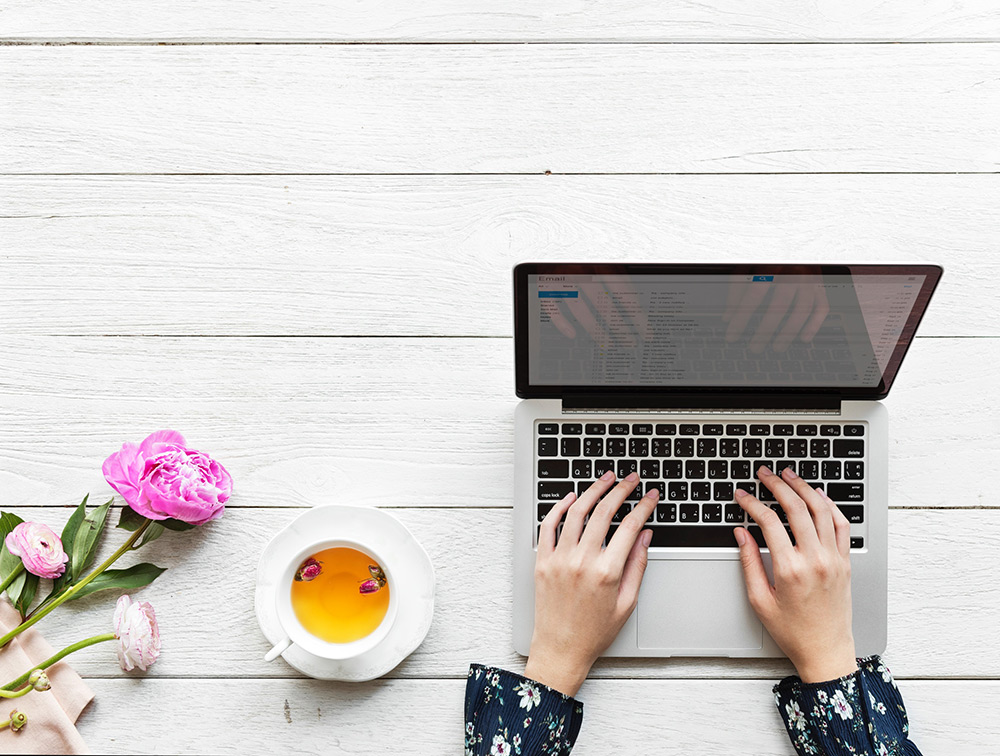 working space detail with laptop teacup flowers