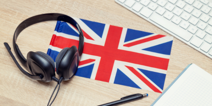 Escritorio con cascos, bandera de Inglaterra, cuaderno, lapicera y teclado  